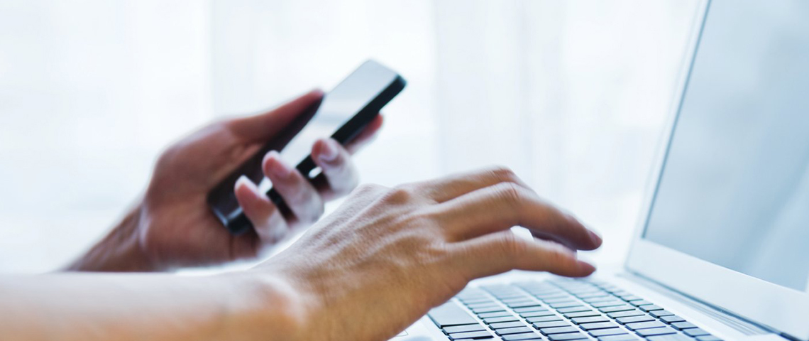 Person using a laptop and a smartphone