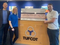 Staff from Tufcot standing next to a wooden stand with a large cheque